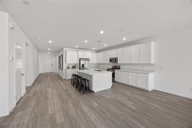3706 Etendre Ct, Las Vegas, NV 89121 - kitchen featuring appliances with stainless steel finishes, a sink, a kitchen bar, light wood finished floors, and white cabinets
