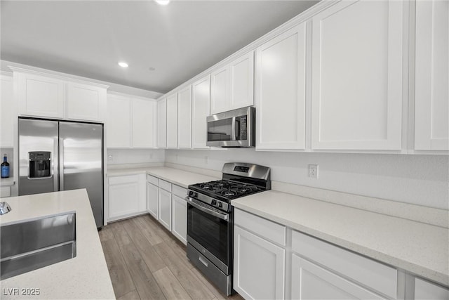3706 Etendre Ct, Las Vegas, NV 89121 - kitchen with appliances with stainless steel finishes, a sink, white cabinetry, recessed lighting, and light wood-style floors
