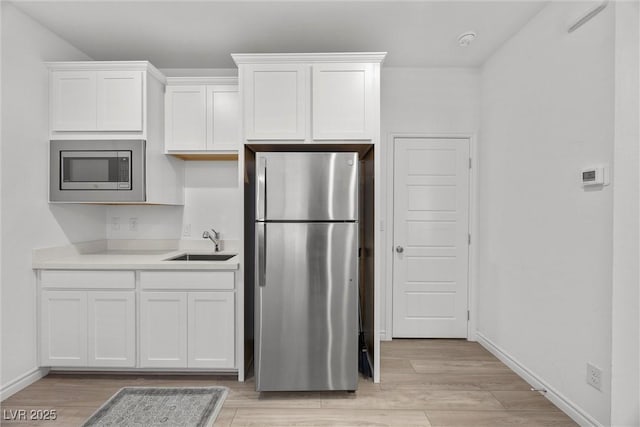 3706 Etendre Ct, Las Vegas, NV 89121 - kitchen with stainless steel appliances, a sink, light wood-type flooring, and white cabinets