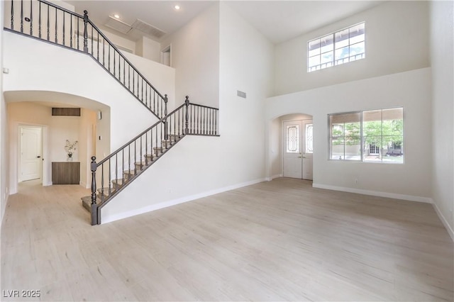 3065 Blue Monaco St, Las Vegas, NV 89117 - foyer featuring arched walkways, a towering ceiling, wood finished floors, stairs, and healthy amount of natural light