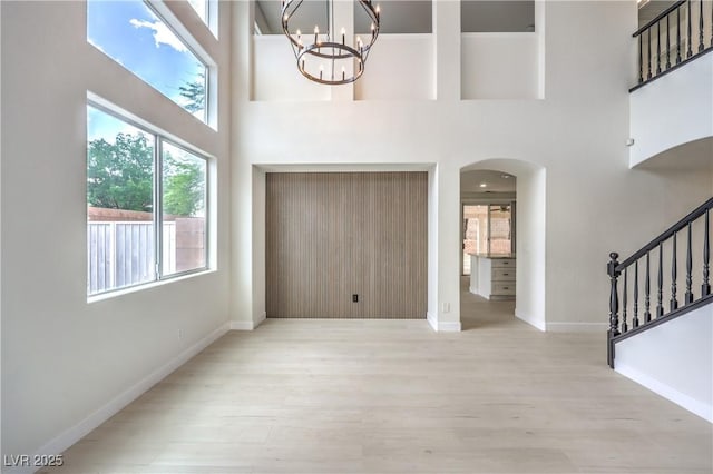 3065 Blue Monaco St, Las Vegas, NV 89117 - foyer entrance featuring arched walkways, a chandelier, wood finished floors, a high ceiling, and stairs