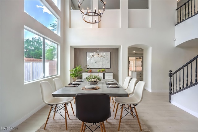 3065 Blue Monaco St, Las Vegas, NV 89117 - dining space featuring a chandelier, arched walkways, a high ceiling, light wood finished floors, and stairs