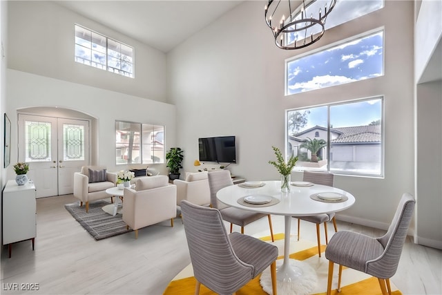3065 Blue Monaco St, Las Vegas, NV 89117 - dining space featuring a towering ceiling, healthy amount of natural light, a chandelier, arched walkways, and light wood-style floors