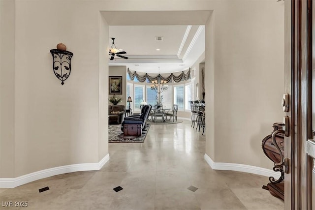 foyer entrance featuring a chandelier, a tray ceiling, baseboards, and ornamental molding