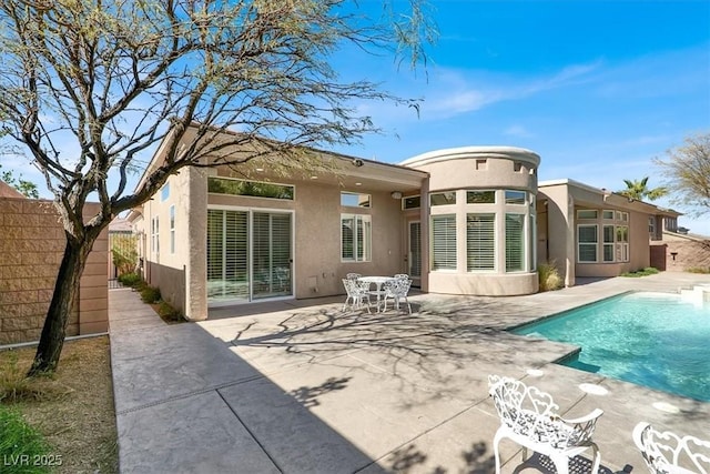 rear view of house featuring stucco siding, a patio, an outdoor pool, and fence