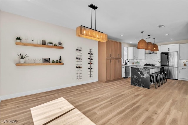 1551 Boundary Peak Way, Las Vegas, NV 89135 - kitchen featuring appliances with stainless steel finishes, a kitchen breakfast bar, light wood finished floors, baseboards, and recessed lighting