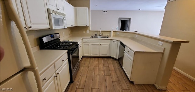 9000 Las Vegas Blvd Unit 1250, Las Vegas, NV 89123 - kitchen featuring appliances with stainless steel finishes, a sink, a peninsula, wood finish floors, and light countertops