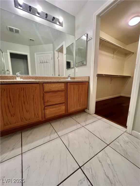 6545 Netherseal Ave, Las Vegas, NV 89139 - bathroom with marble look tile flooring, double vanity, a walk in closet, and baseboards
