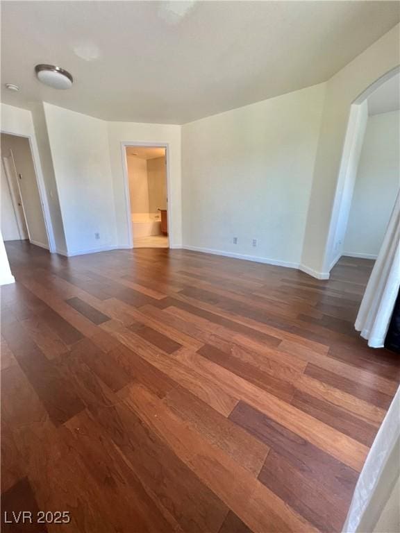 6545 Netherseal Ave, Las Vegas, NV 89139 - spare room featuring dark wood-style flooring, arched walkways, and baseboards
