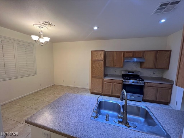 6545 Netherseal Ave, Las Vegas, NV 89139 - kitchen featuring stainless steel gas range, under cabinet range hood, a chandelier, light tile patterned flooring, and brown cabinets