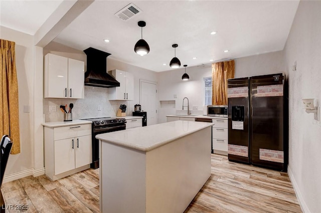 1414 S 13th St, Las Vegas, NV 89104 - kitchen with black appliances, wall chimney range hood, light wood-type flooring, light countertops, and recessed lighting