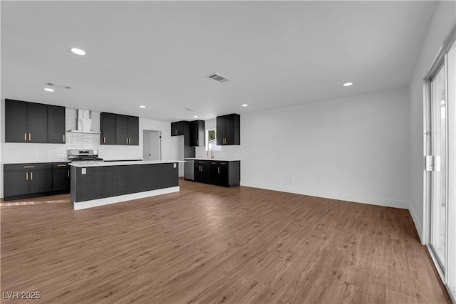 2058 Citroen St, Las Vegas, NV 89142 - kitchen with wall chimney exhaust hood, dark cabinetry, appliances with stainless steel finishes, recessed lighting, and a center island