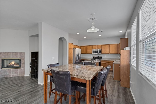 dining room featuring baseboards, dark wood finished floors, a fireplace, and recessed lighting