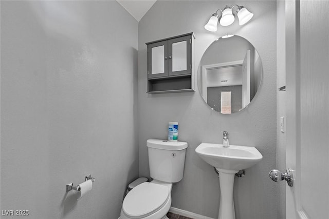 bathroom with toilet, lofted ceiling, and baseboards