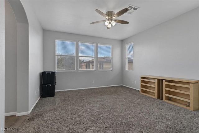 carpeted empty room featuring ceiling fan, arched walkways, and baseboards