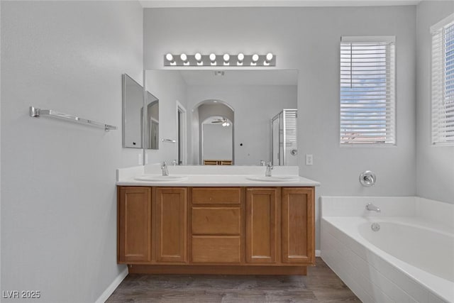 bathroom with a garden tub, double vanity, a stall shower, and wood finished floors