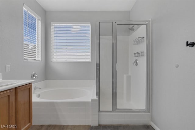 full bath with a stall shower, a bath, vanity, and wood finished floors