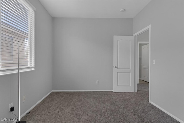 empty room with carpet floors, healthy amount of natural light, and baseboards