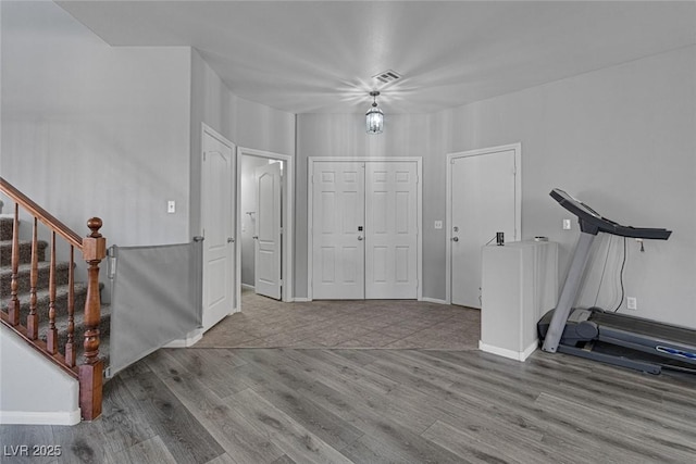 foyer entrance featuring wood finished floors, stairway, and baseboards