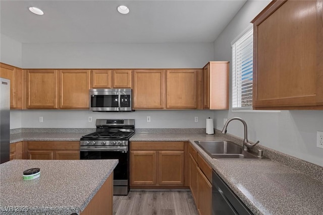 kitchen with stainless steel appliances, a sink, light wood-style flooring, light countertops, and recessed lighting