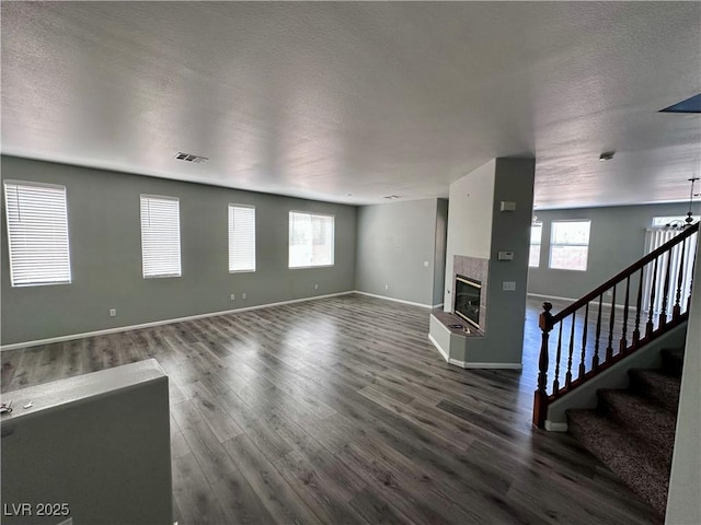 3964 Irvin Ave, Las Vegas, NV 89141 - unfurnished living room with wood finished floors, a fireplace, plenty of natural light, stairs, and a textured ceiling