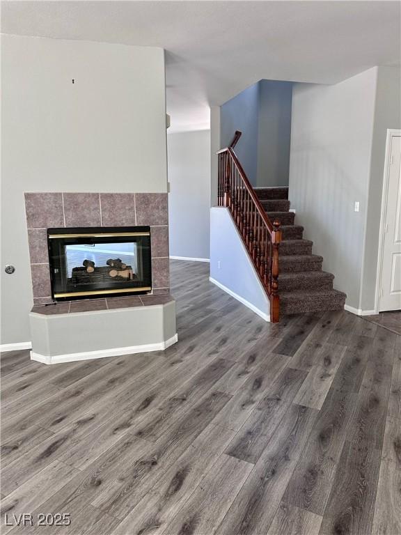 3964 Irvin Ave, Las Vegas, NV 89141 - unfurnished living room featuring wood finished floors, stairway, and a tile fireplace