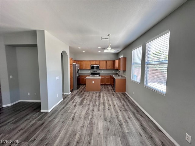3964 Irvin Ave, Las Vegas, NV 89141 - kitchen featuring appliances with stainless steel finishes, open floor plan, light countertops, wood finished floors, and brown cabinetry
