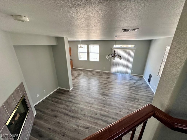 3964 Irvin Ave, Las Vegas, NV 89141 - unfurnished living room with wood finished floors, a textured ceiling, a fireplace, and a chandelier