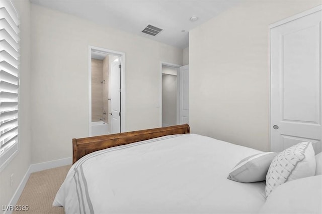 bedroom with light carpet, baseboards, and ensuite bath