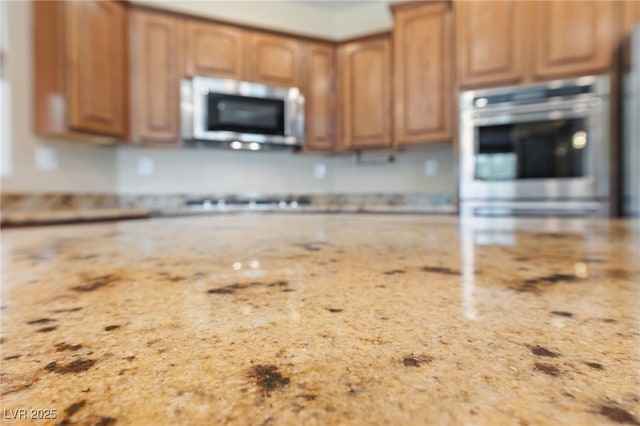 8547 Benidorm Ave, Las Vegas, NV 89178 - kitchen with appliances with stainless steel finishes, light stone counters, and brown cabinetry