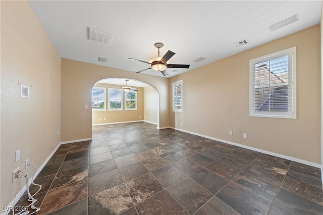 8547 Benidorm Ave, Las Vegas, NV 89178 - empty room with stone tile floors, ceiling fan, baseboards, and arched walkways