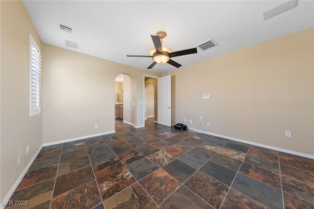8547 Benidorm Ave, Las Vegas, NV 89178 - unfurnished room featuring baseboards, arched walkways, ceiling fan, and stone tile floors