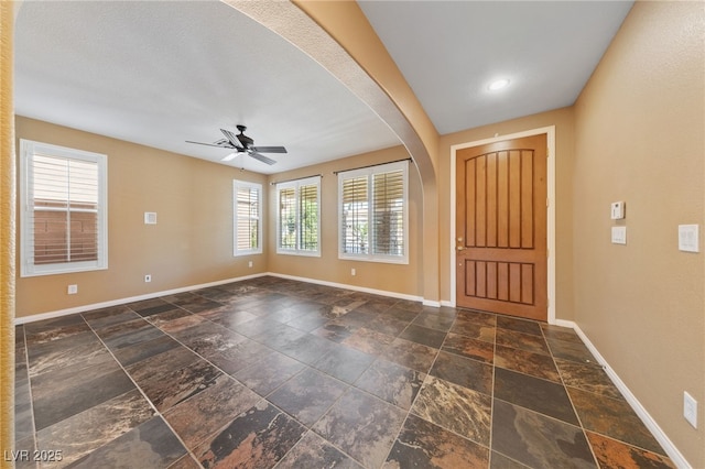 8547 Benidorm Ave, Las Vegas, NV 89178 - foyer entrance featuring baseboards, stone tile flooring, a ceiling fan, and arched walkways