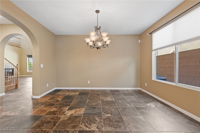 8547 Benidorm Ave, Las Vegas, NV 89178 - spare room with baseboards, a chandelier, arched walkways, stairway, and stone finish floors