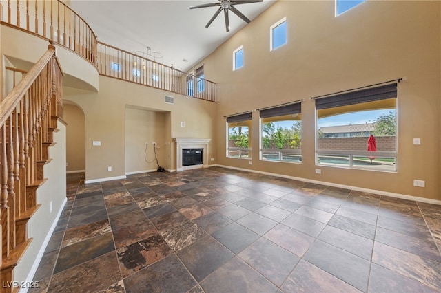 8547 Benidorm Ave, Las Vegas, NV 89178 - unfurnished living room with ceiling fan, healthy amount of natural light, baseboards, a towering ceiling, and a glass covered fireplace