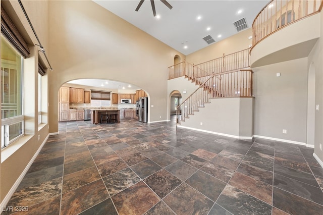 8547 Benidorm Ave, Las Vegas, NV 89178 - unfurnished living room with arched walkways, a high ceiling, baseboards, and stone tile floors
