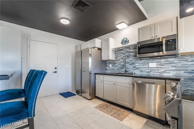 3145 Tarpon Dr, Las Vegas, NV 89120 - kitchen with appliances with stainless steel finishes, light marble finish flooring, a sink, dark countertops, and decorative backsplash