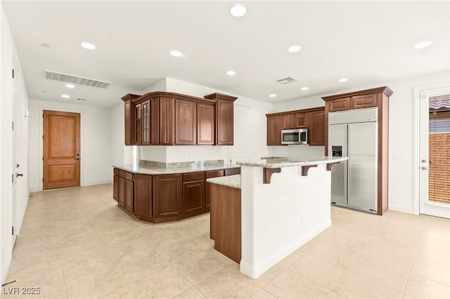 1252 Casa Palermo Cir, Henderson, NV 89011 - kitchen with appliances with stainless steel finishes, a breakfast bar, recessed lighting, a kitchen island, and light stone counters