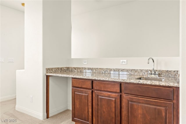 1252 Casa Palermo Cir, Henderson, NV 89011 - kitchen featuring a sink, light colored carpet, baseboards, and light stone countertops