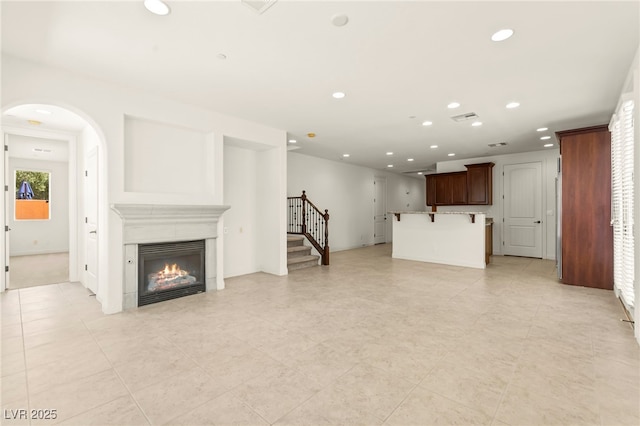 1252 Casa Palermo Cir, Henderson, NV 89011 - unfurnished living room with stairs, recessed lighting, a glass covered fireplace, light tile patterned floors, and baseboards
