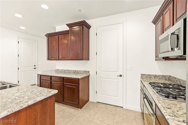 1252 Casa Palermo Cir, Henderson, NV 89011 - kitchen with stainless steel appliances, recessed lighting, light tile patterned floors, baseboards, and light stone counters