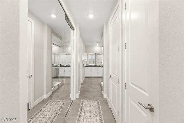 hallway with light tile patterned flooring and baseboards