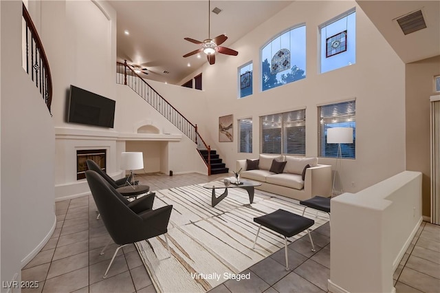 386 Wiseton Ave, Las Vegas, NV 89183 - tiled living area with stairs, a high ceiling, a ceiling fan, baseboards, and a glass covered fireplace