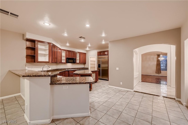 386 Wiseton Ave, Las Vegas, NV 89183 - kitchen featuring stainless steel built in refrigerator, black microwave, arched walkways, a peninsula, and dark stone countertops