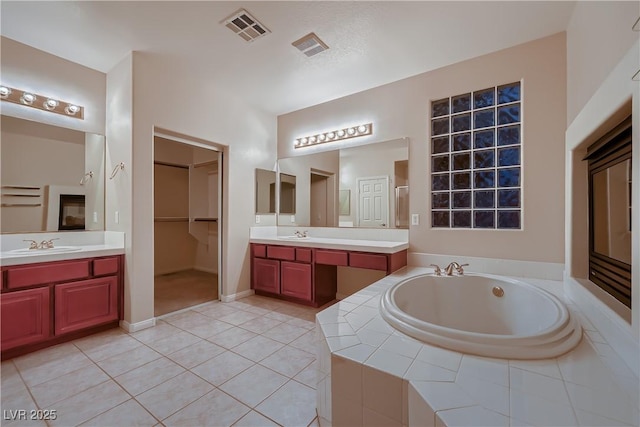 386 Wiseton Ave, Las Vegas, NV 89183 - bathroom featuring a bath, tile patterned floors, two vanities, and a spacious closet