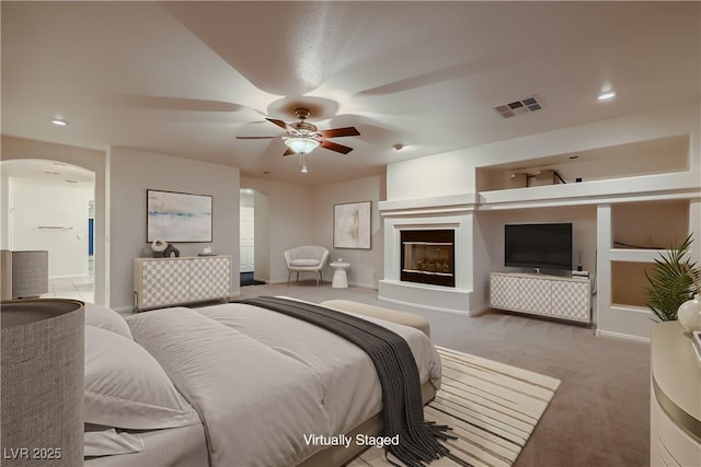 386 Wiseton Ave, Las Vegas, NV 89183 - bedroom featuring carpet flooring, arched walkways, a glass covered fireplace, connected bathroom, and baseboards