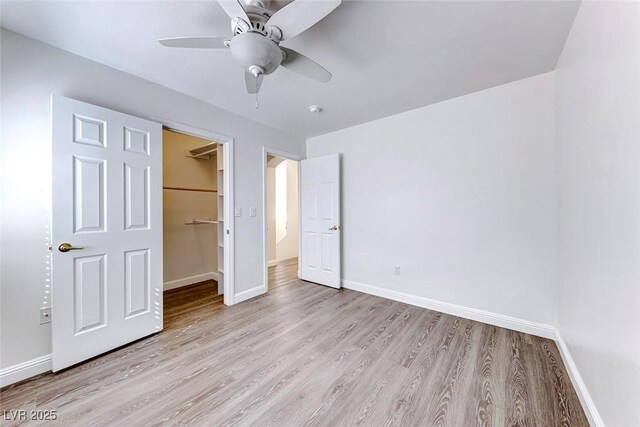 11028 Meadow Leaf Ave, Las Vegas, NV 89144 - unfurnished bedroom featuring light wood-style floors, baseboards, a walk in closet, and a closet
