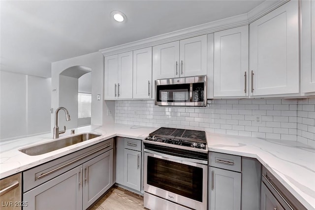 11028 Meadow Leaf Ave, Las Vegas, NV 89144 - kitchen with stainless steel appliances, a sink, gray cabinetry, light stone countertops, and backsplash