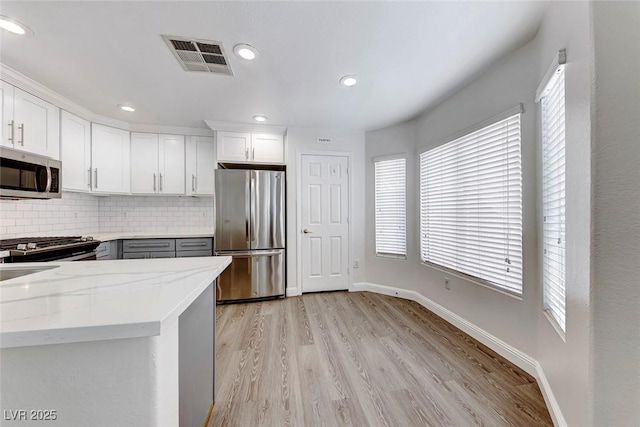 11028 Meadow Leaf Ave, Las Vegas, NV 89144 - kitchen featuring appliances with stainless steel finishes, tasteful backsplash, light stone counters, baseboards, and light wood-style flooring