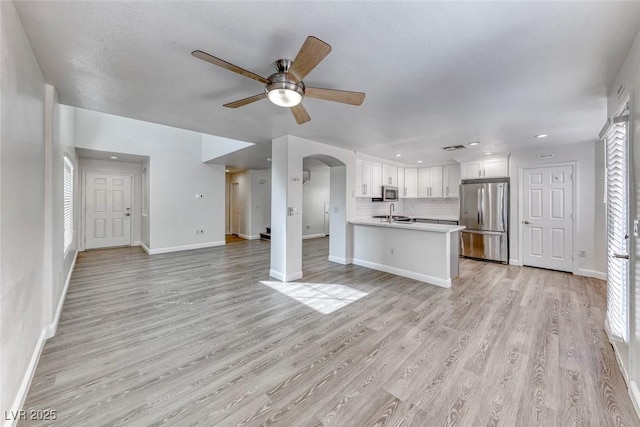 11028 Meadow Leaf Ave, Las Vegas, NV 89144 - unfurnished living room featuring ceiling fan, arched walkways, light wood-style floors, baseboards, and recessed lighting